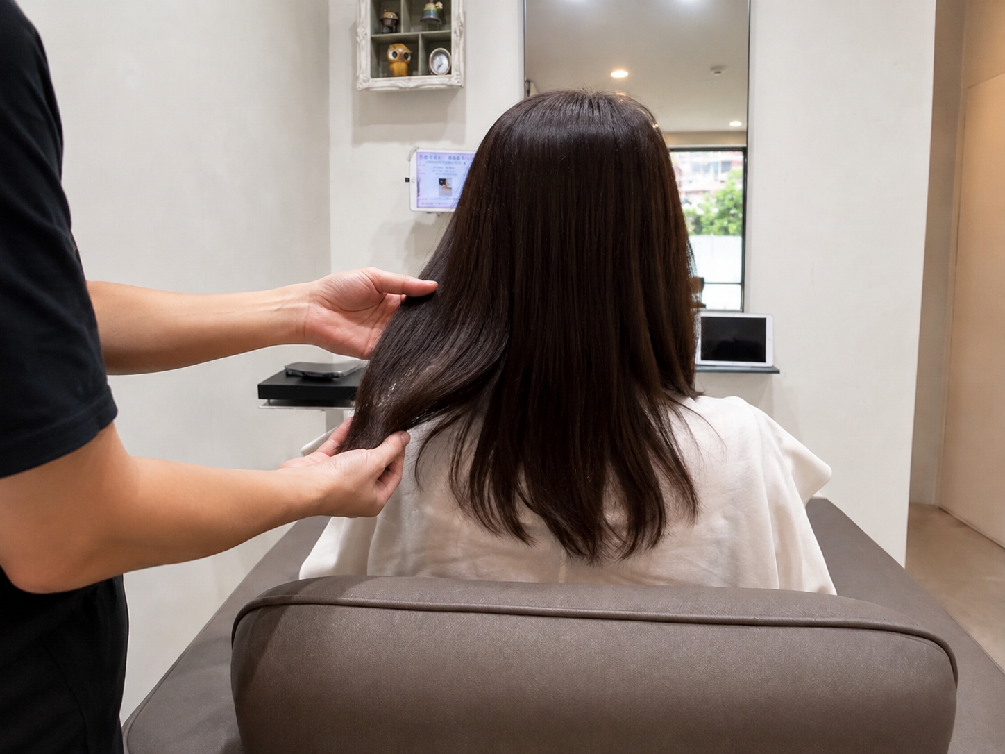 美容師が髪を手に取り、毛先のまとまりやツヤ、膨らみを確認している様子。施術後の髪の状態を後ろ姿でチェックしている写真
